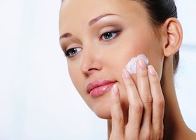 Young beautiful woman caring of her face with moisturizer cream